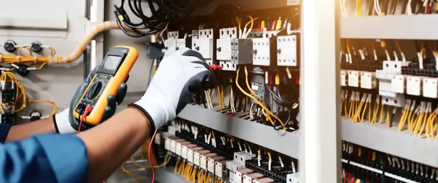 Electrician testing the wiring in a commercial control panel with a multimeter
