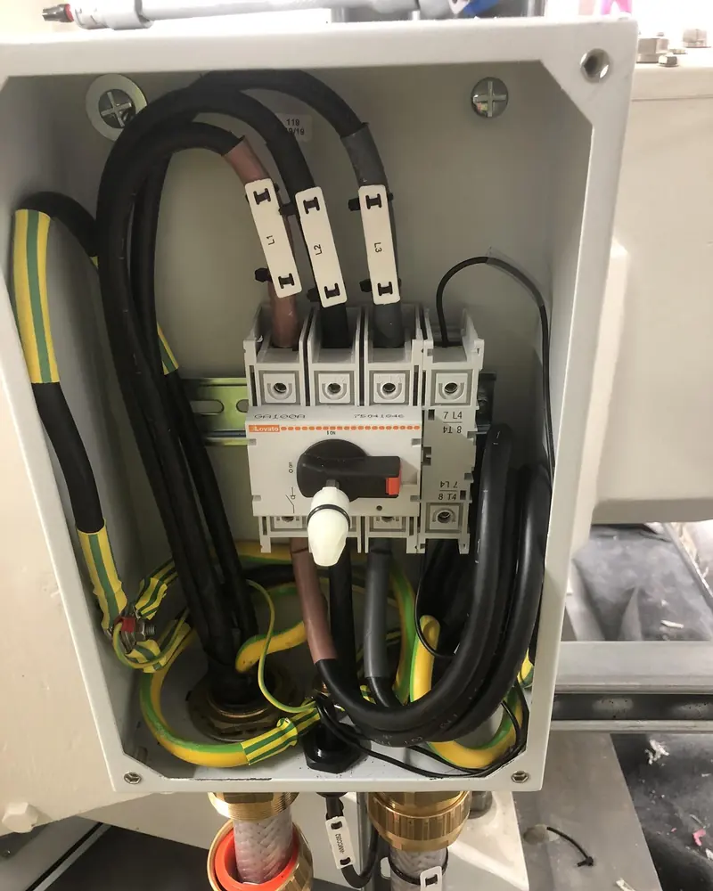 Three-phase rotary isolator wired inside a steel enclosure, with the L1, L2 and L3 cables marked